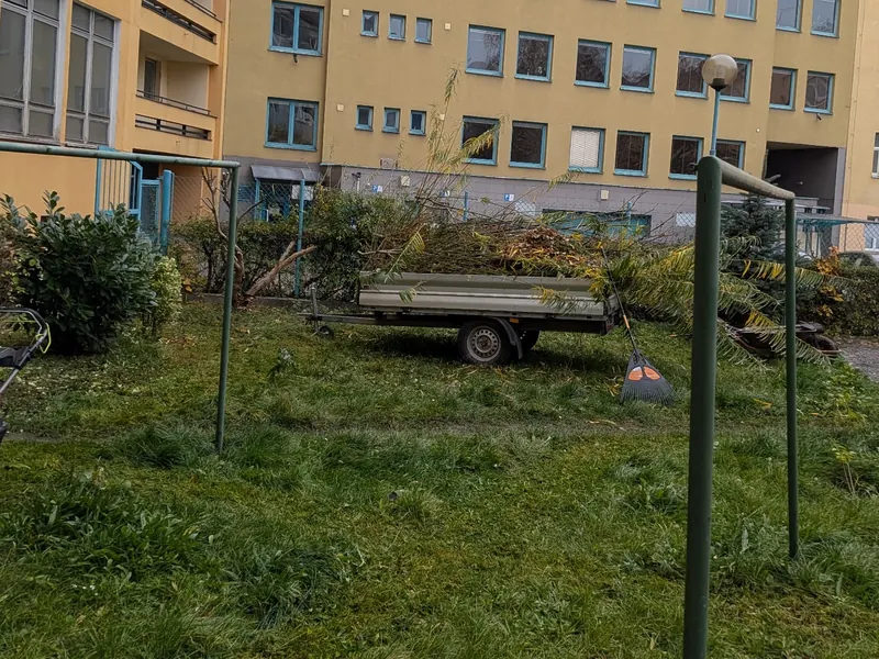 Údržba společné zeleně u bytových domů v Hradci Králové s přívěsem naplněným odstraněnou vegetací.